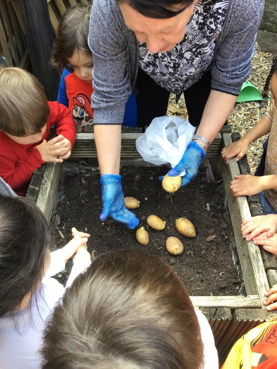 destiny haven nursery children gather around a wooden planter