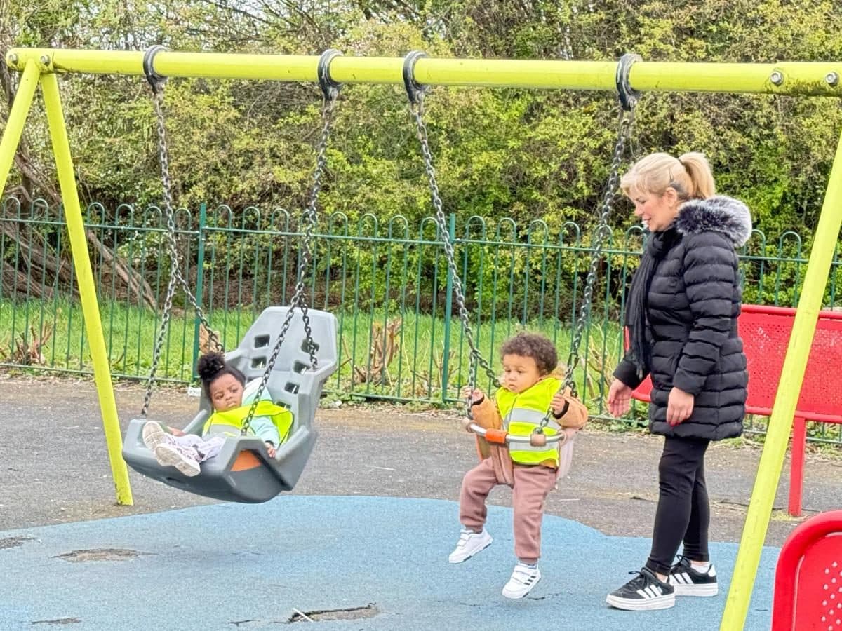 a destiny haven nursery practitioner supervises nursery children enjoying swings